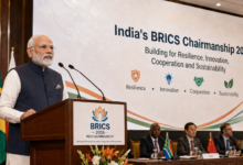 India's BRICS Chairmanship 2026 event showing Prime Minister Narendra Modi speaking at a BRICS podium in front of delegates and the four key pillars backdrop